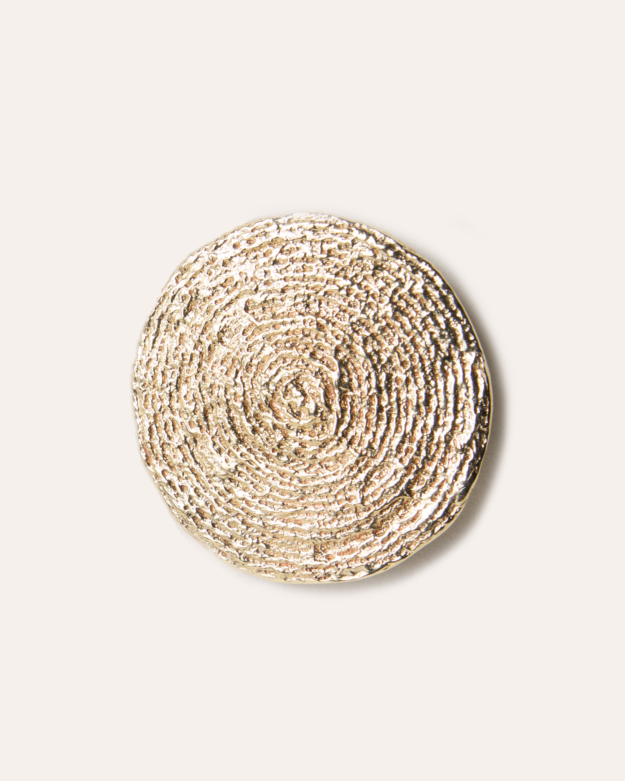 Round, cast brooch on a light beige background
