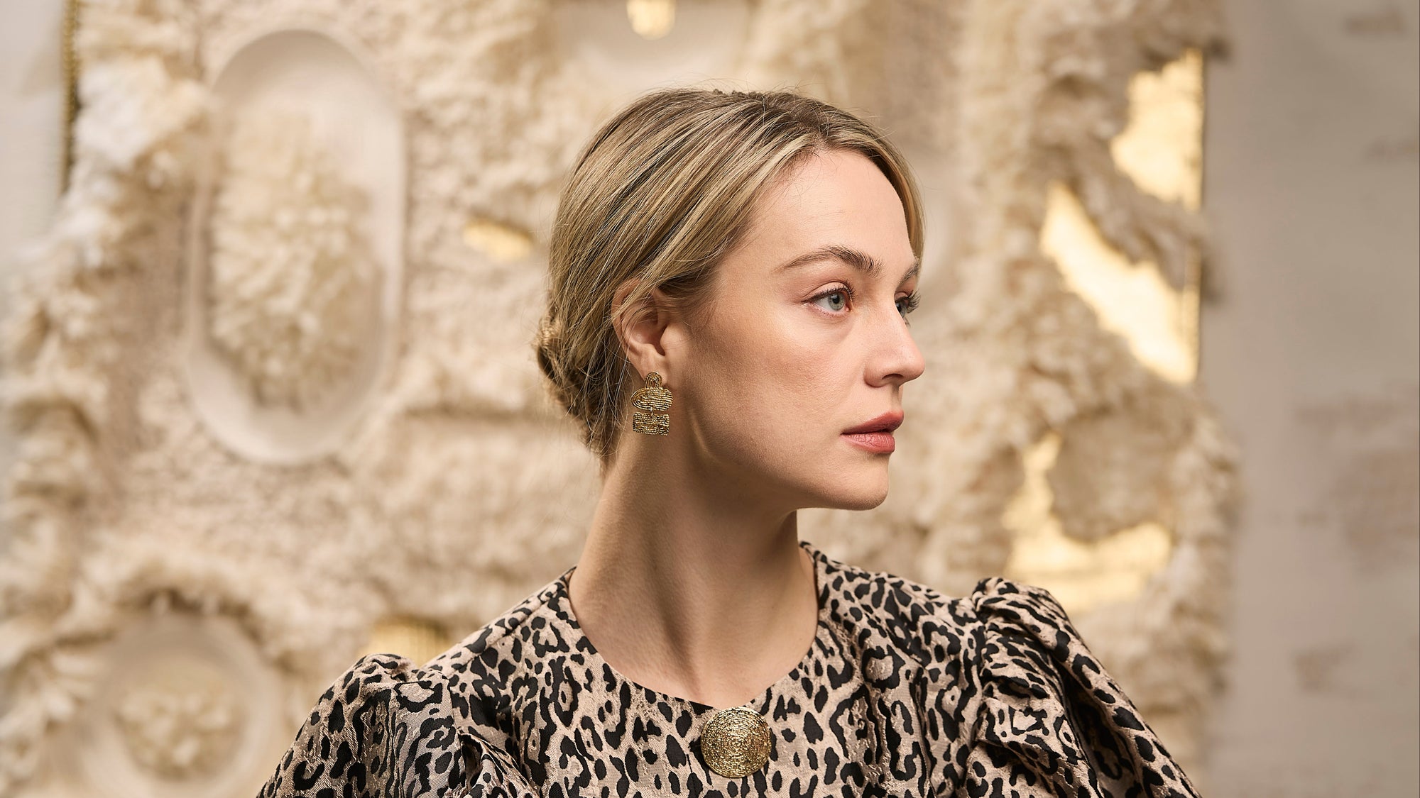 Woman wearing a leopard print dress with a decorative wall in the background