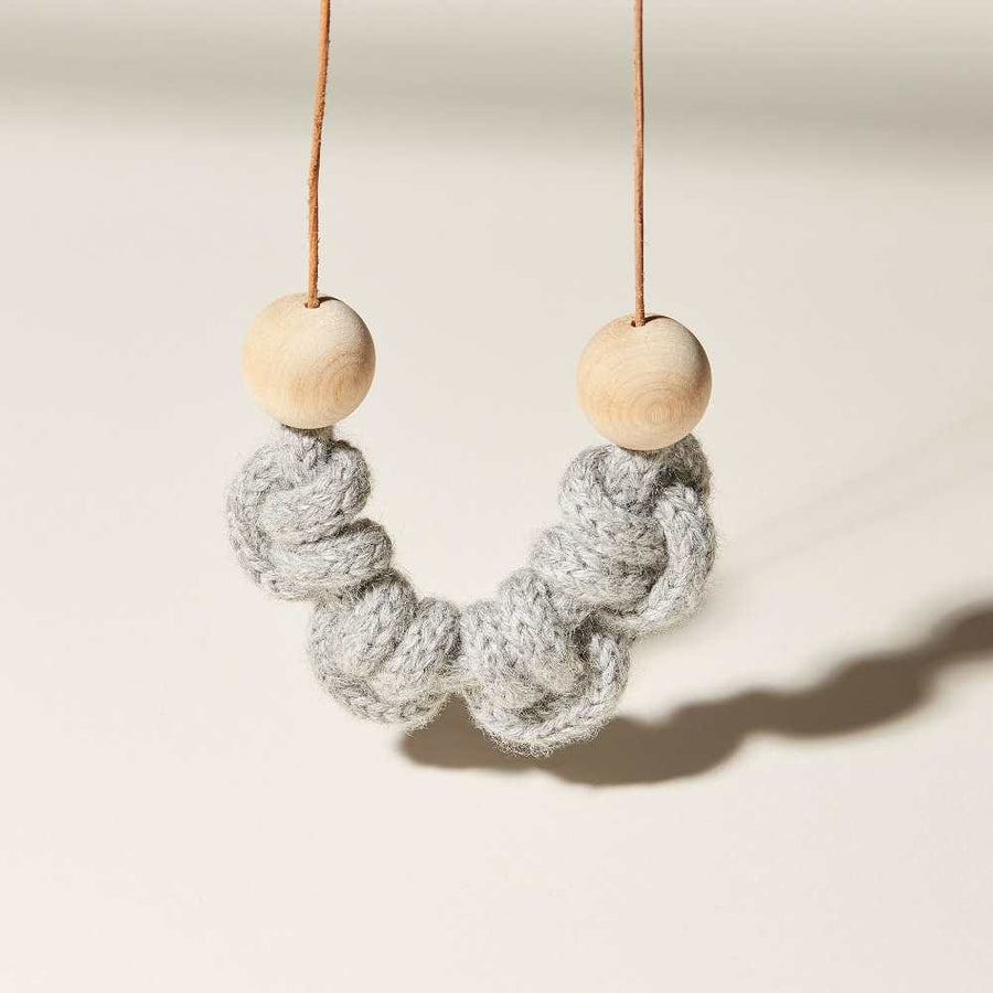 A macramé styled necklace. Four hitch knots of baby alpaca iCord are finishes with wood beads and a round-cut leather cord.