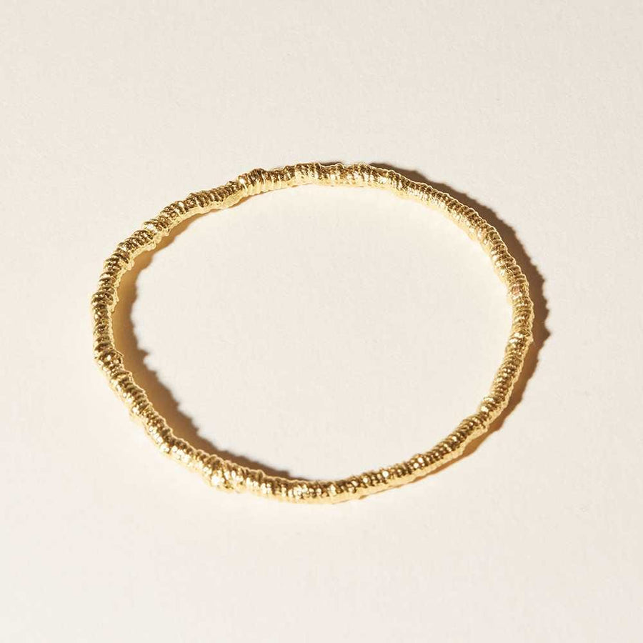 Coiled threads of cotton has been cast into brilliant 14k gold plate. organically shaped bangle.