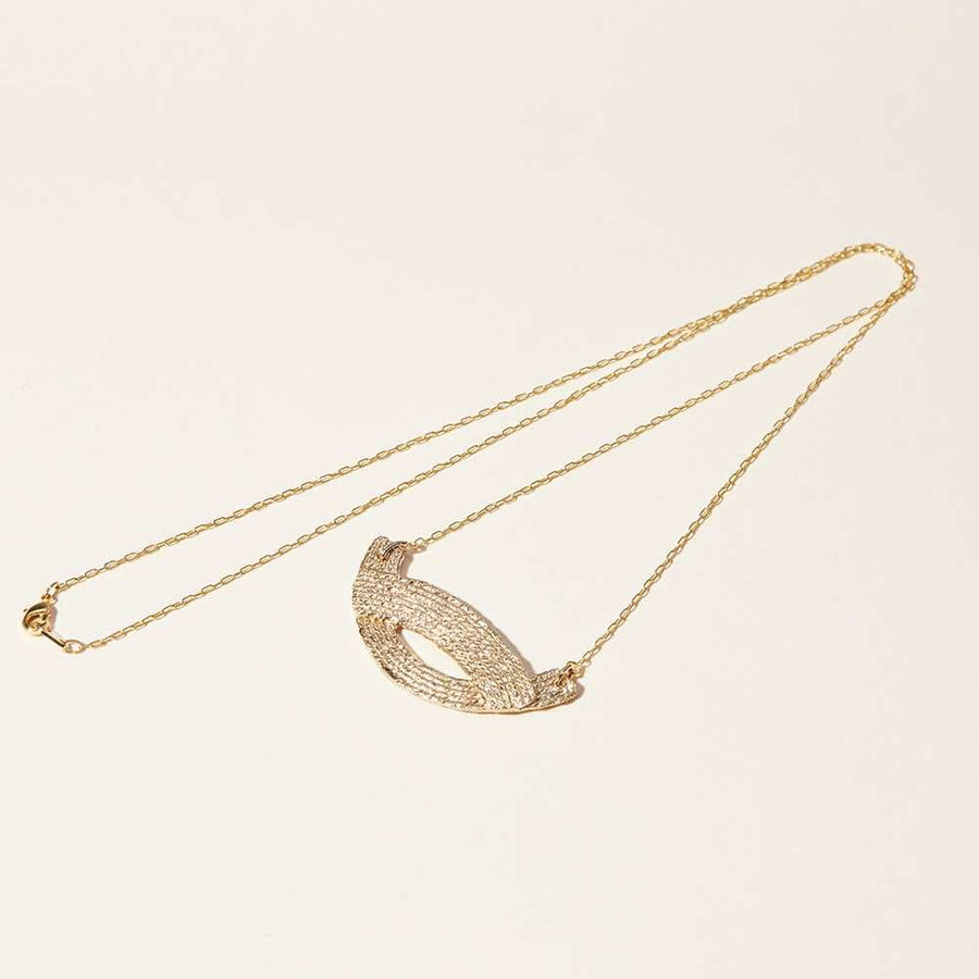 Two converging arcs of textured and thread-like quality of the Waves Pendant Necklace by Cog. 