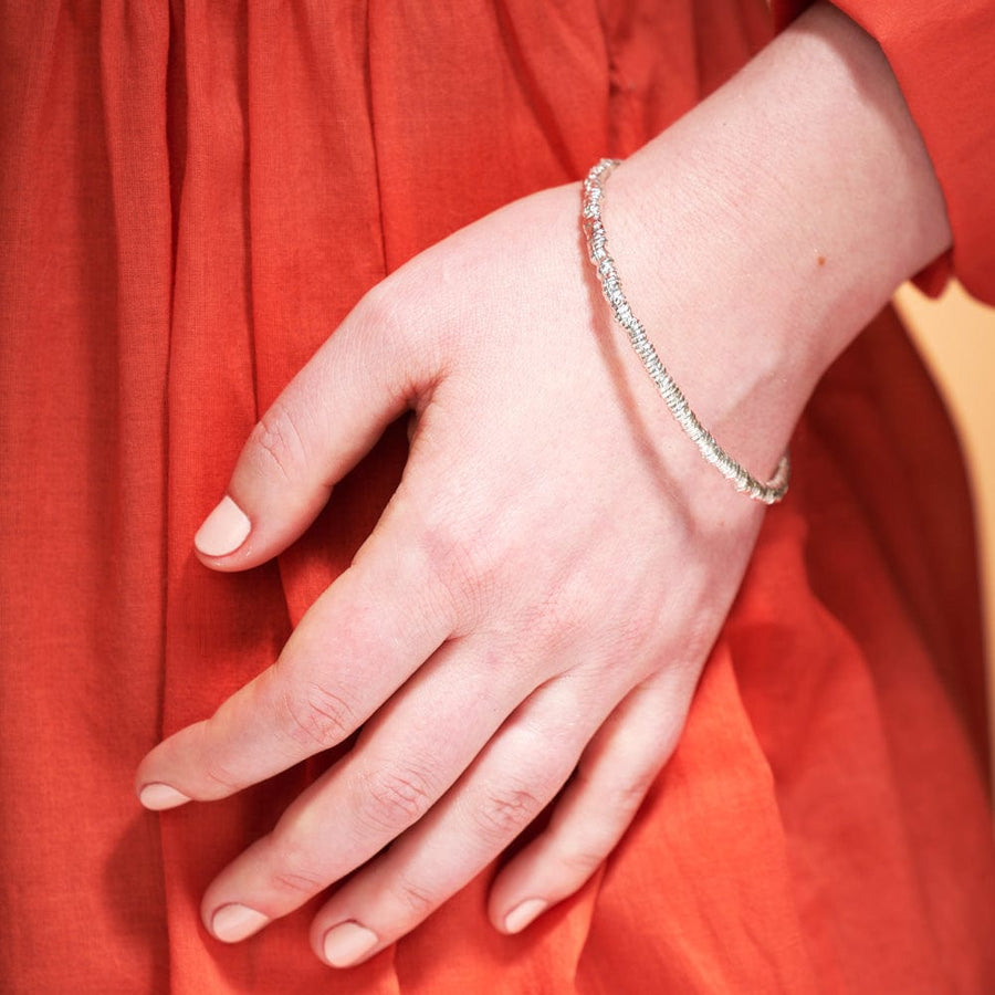 A model is wearing the Harriet Bracelet. Shown in Sterling SIlver. The pattern of the bracelet was created by gathering cotton along 3-ply cord 