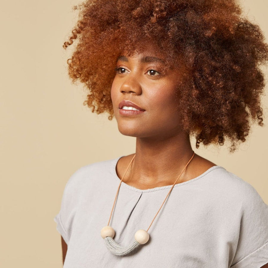 A model wears the Helm Necklace made of natural materials: baby alpaca, natural wooden beads and round cut leather. 