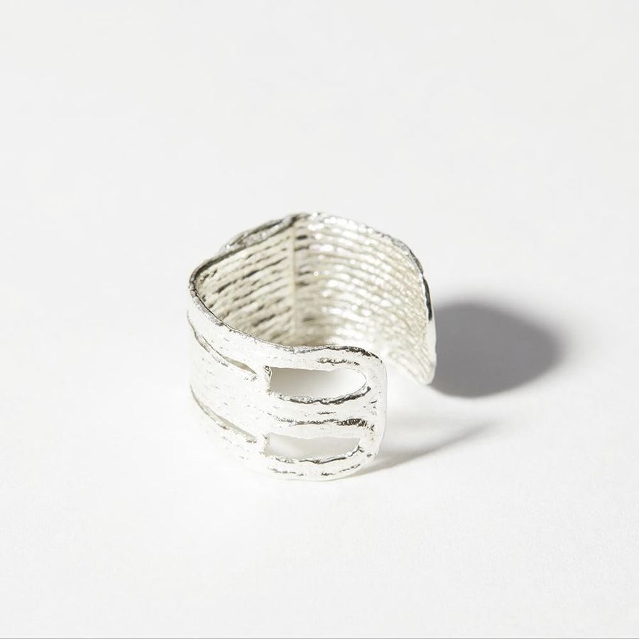 The sterling silver version of the Totem Ring which is adjustable with a 3/8 width. It features a unique texture and has negative shape detials.