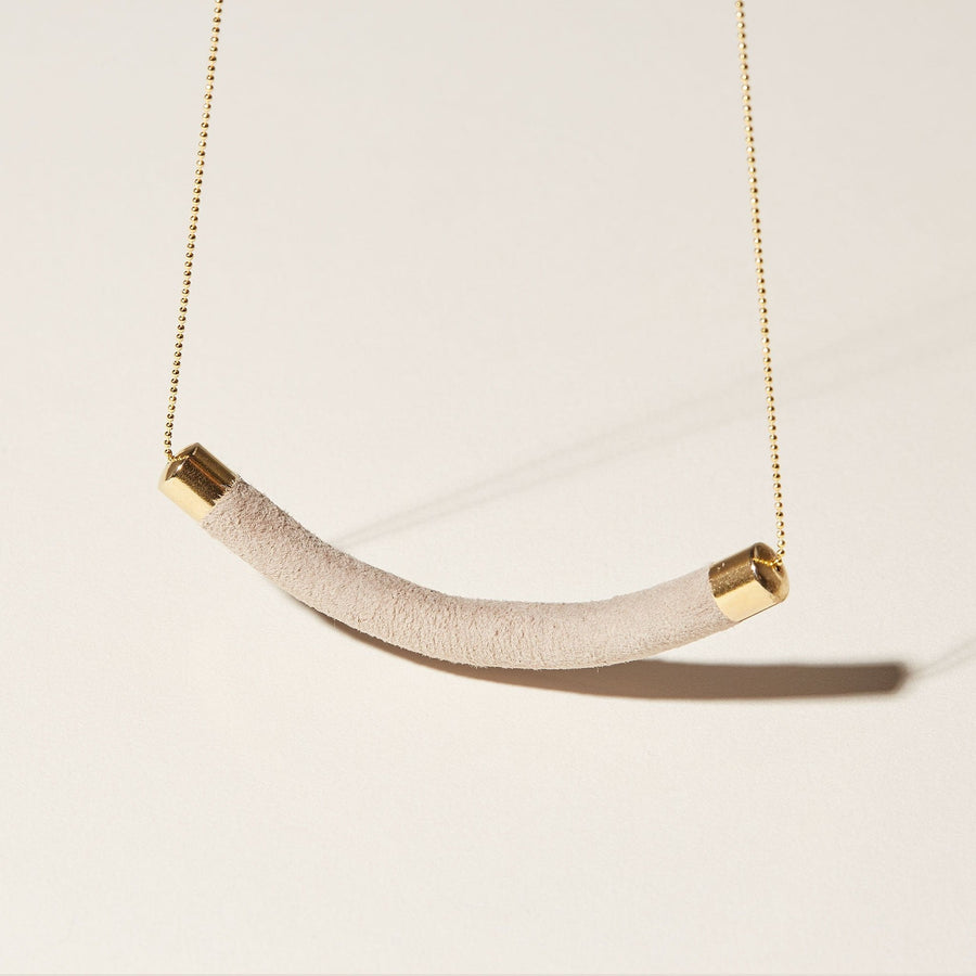The Crescent Necklace by COG in taupe, suede lambskin leather. The soft pendant hangs from a gold plated bead chain. 